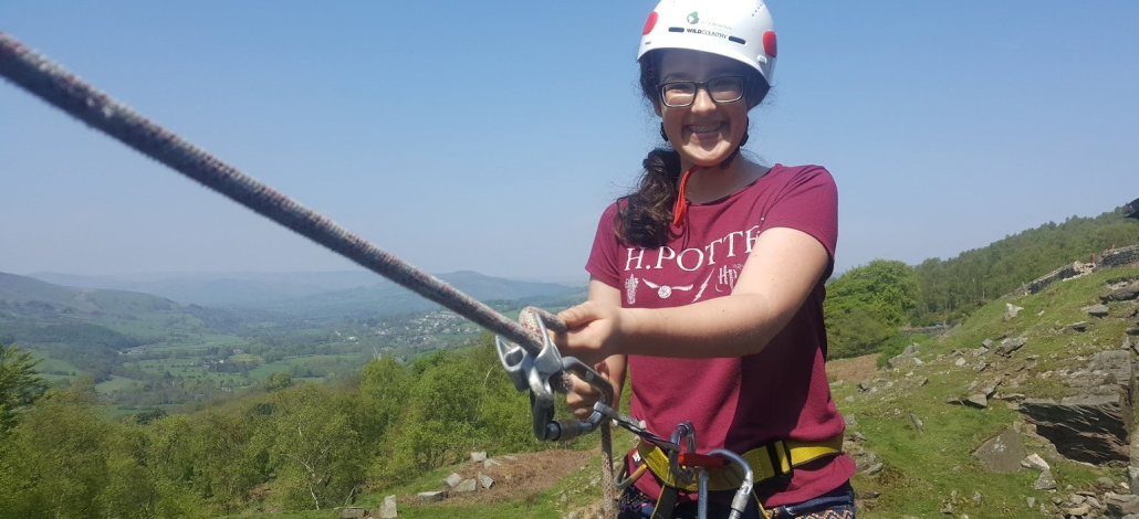 image showing a smiling girl about to abseil, in the Peak District